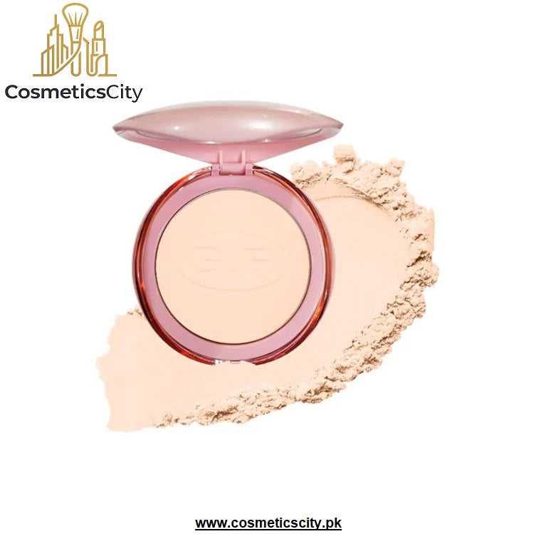 An open round compact of pressed powder in a translucent pink case, shown with a smear of the light beige powder on a white background. The brand name 'CosmeticsCity' is visible in the top left corner.