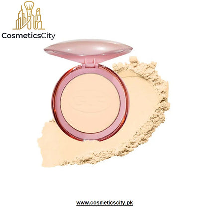 An open round compact of pressed powder foundation or bronzer with a translucent pink lid, shown with a smear of the light beige powder on a white background. The brand name 'CosmeticsCity' is visible in the top left corner.