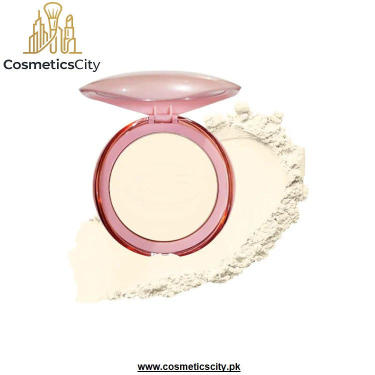 A round compact of pressed powder with a translucent pink lid and rim, shown open with a smear of the light beige powder behind it on a white background. The brand name 'CosmeticsCity' is visible in the top left corner.